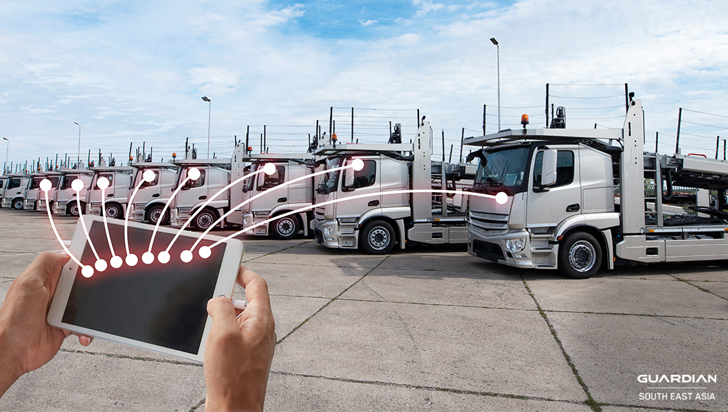 man holding tablet infront of trucks